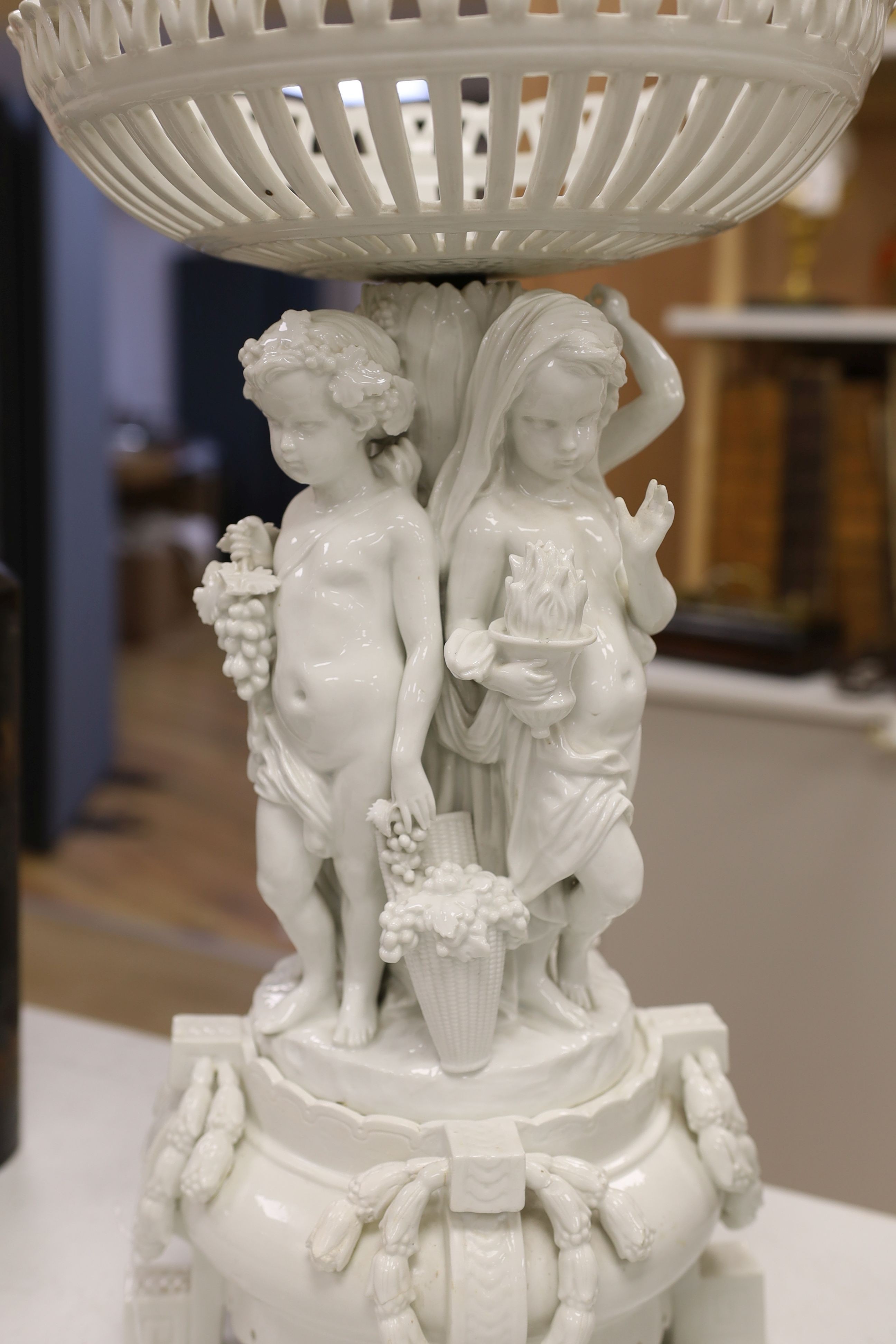 A large Continental white glazed porcelain centrepiece, the stem modelled with with figures emblematic of the four seasons, approx 53cm tall